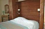 This cozy bedroom features a rustic wooden headboard and matching wardrobe, creating a warm and inviting atmosphere.