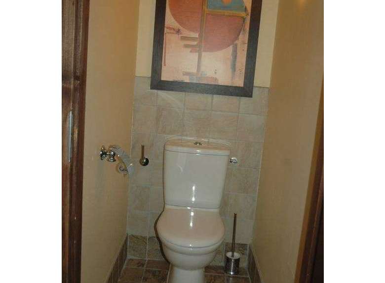 This cozy bathroom features a modern toilet and a stylish framed artwork, creating a comfortable and inviting space.