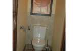 This cozy bathroom features a modern toilet and a stylish framed artwork, creating a comfortable and inviting space.