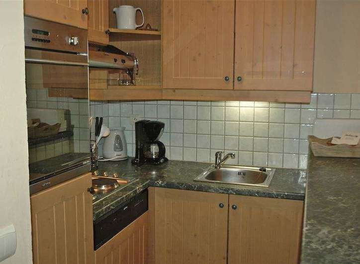 This cozy kitchen features wooden cabinets and a tiled backsplash, creating a warm and inviting atmosphere.