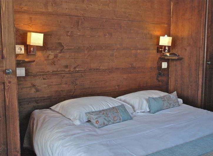 Cozy bedroom with wooden paneling and a comfortable bed.