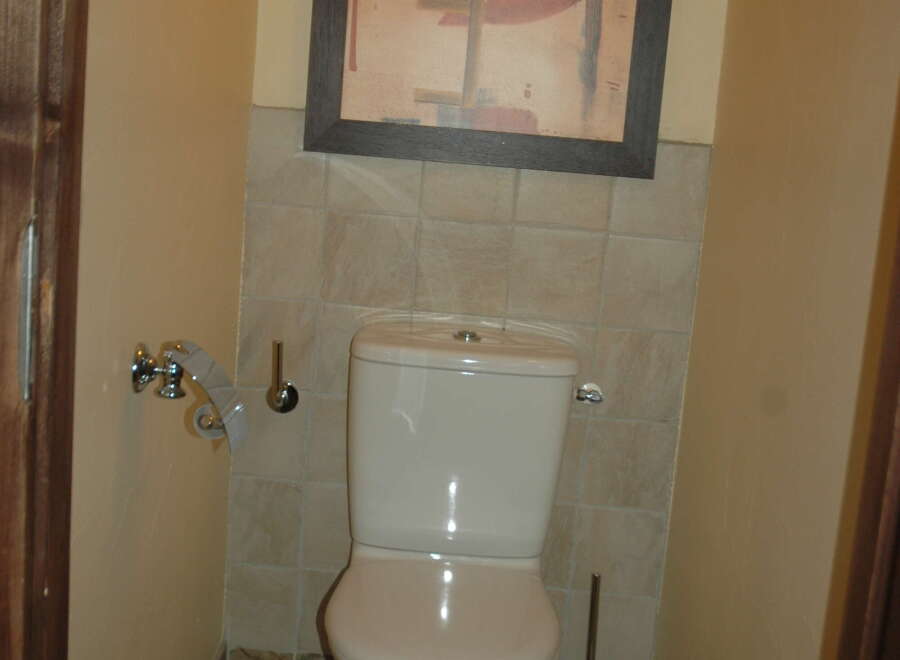 This bathroom features a modern white toilet and a stylish abstract art piece hanging above.