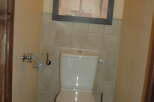 This bathroom features a modern white toilet and a stylish abstract art piece hanging above.