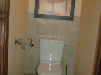 This bathroom features a modern white toilet and a stylish abstract art piece hanging above.