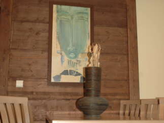 Experience elegant dining in this beautifully appointed space, featuring a striking abstract art piece and a unique decorative vase.