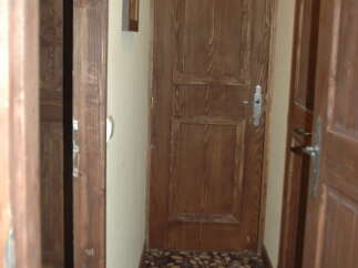 Discover a charming hallway featuring warm wooden doors and a richly patterned carpet.