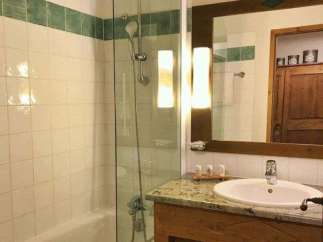 This charming bathroom features a sleek glass shower enclosure and a classic white sink.