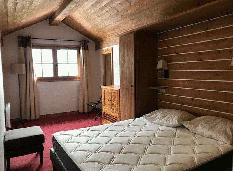 Cozy bedroom with a rustic wooden ceiling and walls, creating a warm and inviting atmosphere.