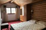 Cozy bedroom with a rustic wooden ceiling and walls, creating a warm and inviting atmosphere.