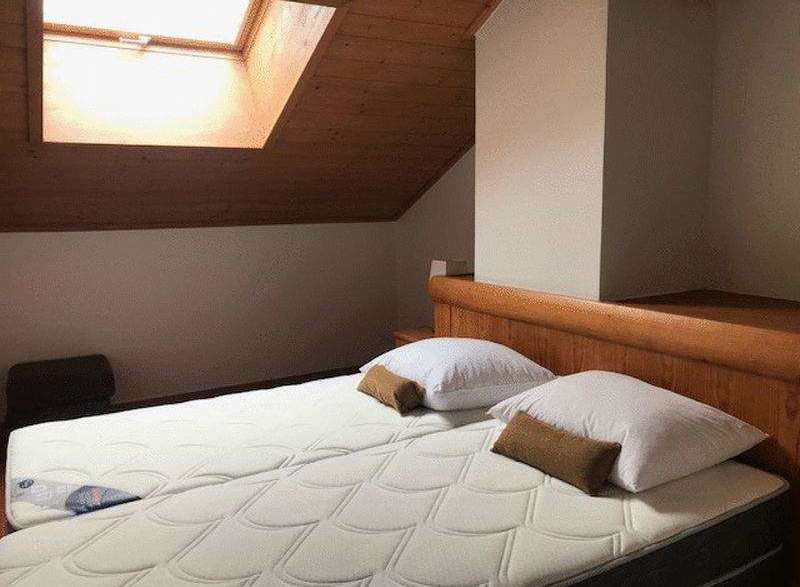 Cozy bedroom with a unique slanted ceiling and a skylight, offering ample natural light.
