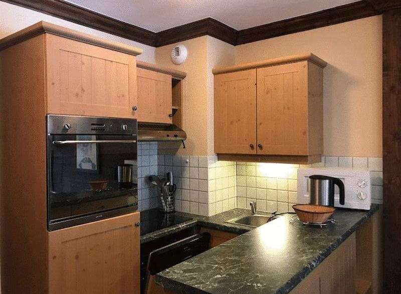 This charming kitchen features wooden cabinetry and a sleek countertop, creating a warm and inviting atmosphere.