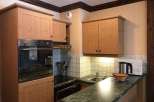 This charming kitchen features wooden cabinetry and a sleek countertop, creating a warm and inviting atmosphere.