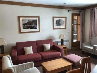 Cozy living room with a comfortable red sofa and two armchairs, perfect for relaxing.