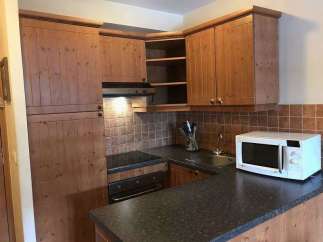 This charming kitchen features wooden cabinetry and a sleek countertop, creating a warm and inviting atmosphere.