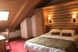 Experience the charm of this cozy attic bedroom, featuring a unique wooden ceiling and walls that create a warm and inviting atmosphere.