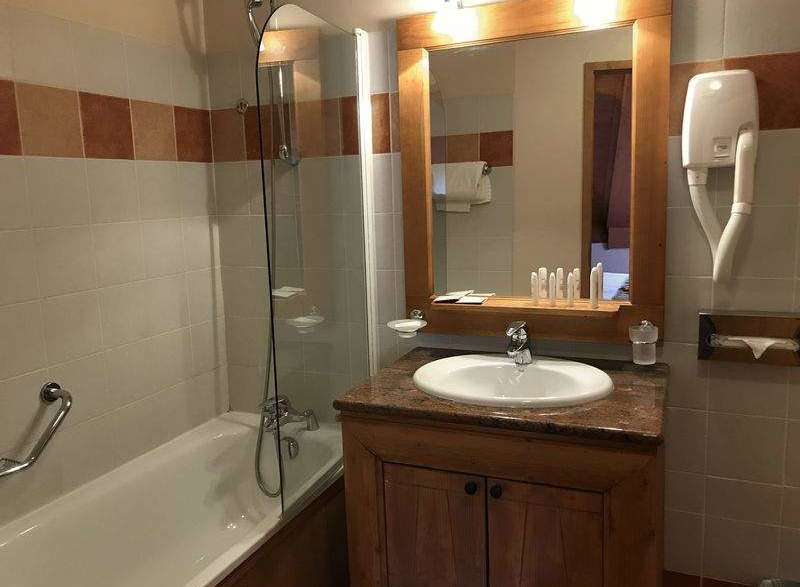 This charming bathroom features a classic design with a wooden vanity and a well-lit mirror.