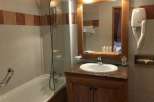 This charming bathroom features a classic design with a wooden vanity and a well-lit mirror.