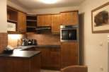 This charming kitchen features warm wooden cabinetry and a modern built-in oven, creating a cozy and functional space.