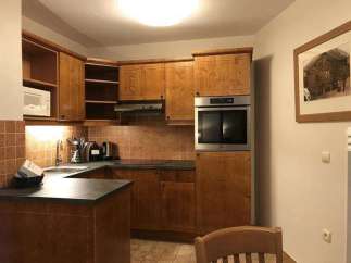 This charming kitchen features warm wooden cabinetry and a modern built-in oven, creating a cozy and functional space.
