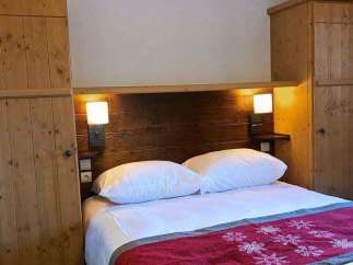 Cozy bedroom with wooden accents and a comfortable bed.