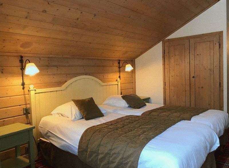 Cozy bedroom with wooden walls and ceiling, creating a warm and inviting atmosphere.