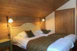 Cozy bedroom with wooden walls and ceiling, creating a warm and inviting atmosphere.