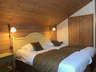 Cozy bedroom with wooden walls and ceiling, creating a warm and inviting atmosphere.
