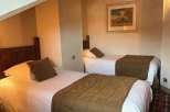 Cozy twin beds in a well-lit room, perfect for a comfortable stay.
