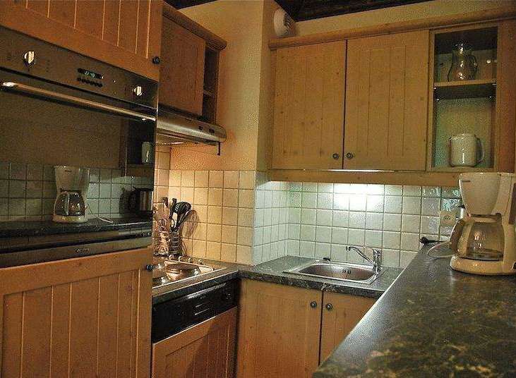 This cozy kitchen features wooden cabinets and a built-in oven, perfect for preparing meals.