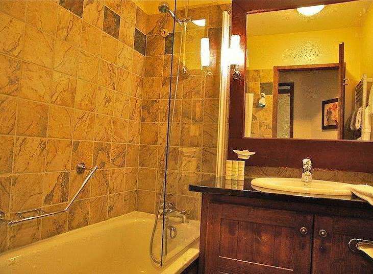 This bathroom features a warm and inviting design with its tiled walls and wooden vanity.