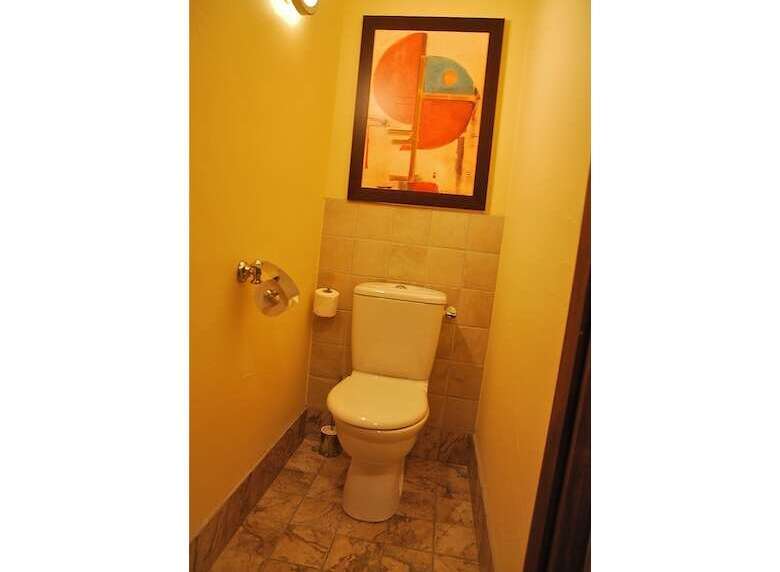 This bathroom features a modern toilet with a tiled backsplash and a framed abstract artwork above.