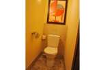 This bathroom features a modern toilet with a tiled backsplash and a framed abstract artwork above.