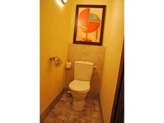 This bathroom features a modern toilet with a tiled backsplash and a framed abstract artwork above.