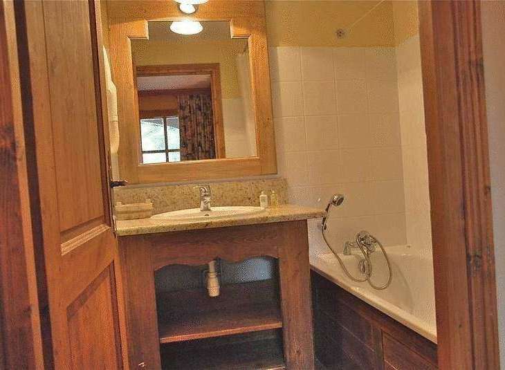 Discover a charming bathroom with a rustic wooden vanity and a built-in bathtub.