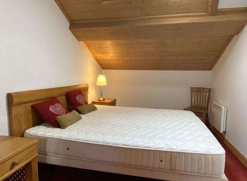 Cozy bedroom with a wooden ceiling and a comfortable bed.