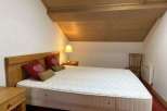 Cozy bedroom with a wooden ceiling and a comfortable bed.