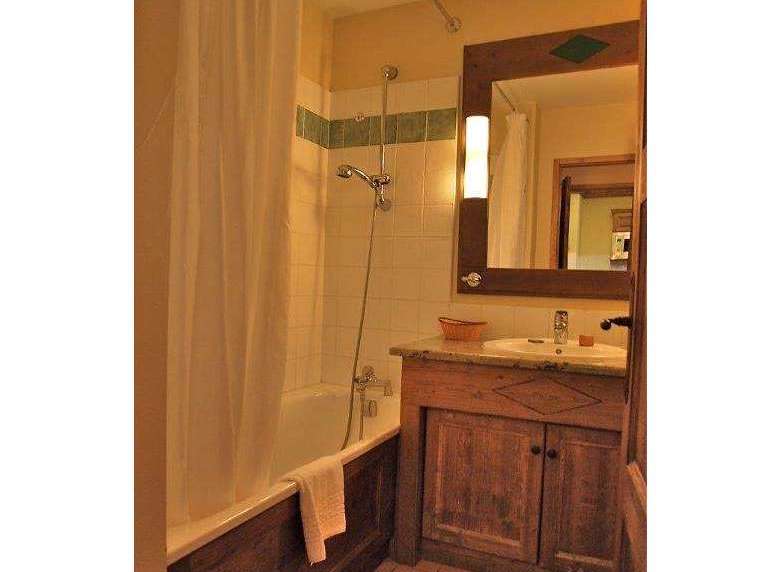 This charming bathroom features a rustic wooden vanity and a classic bathtub with a shower.
