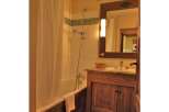 This charming bathroom features a rustic wooden vanity and a classic bathtub with a shower.