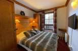 Cozy bedroom with wooden accents and a comfortable bed.