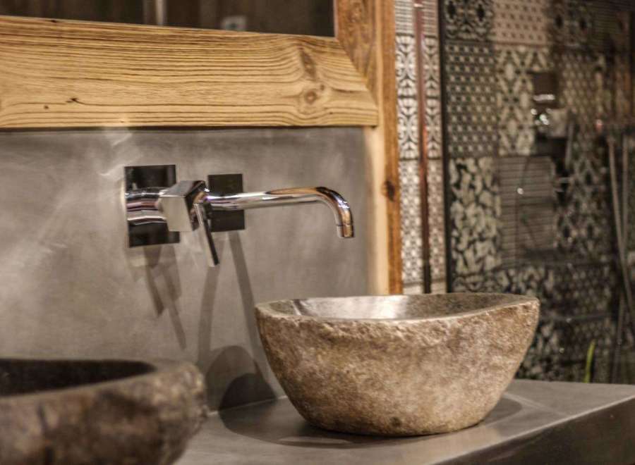 This bathroom boasts a unique stone sink and a sleek chrome faucet, creating a modern yet natural aesthetic.