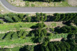 Aerial view of a paved path curving through a lush green forest.