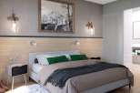 This stunning bedroom boasts a cozy and modern design, featuring a plush bed with a soft throw blanket and stylish green pillows.