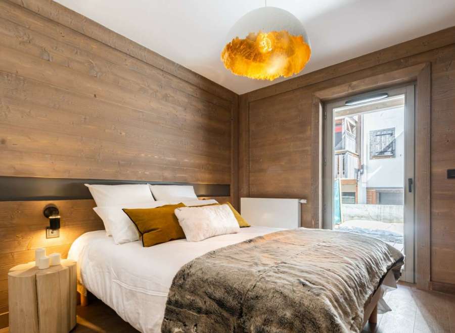 Cozy bedroom with wooden walls and a comfy bed, perfect for a relaxing stay.