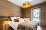 Cozy bedroom with wooden walls and a comfy bed, perfect for a relaxing stay.