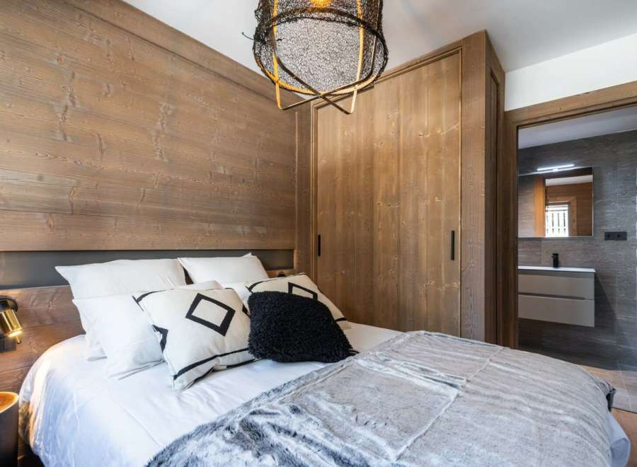 Cozy bedroom with wooden walls and a plush bed, perfect for a relaxing getaway.