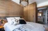 Cozy bedroom with wooden walls and a plush bed, perfect for a relaxing getaway.