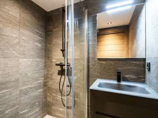 Modern bathroom with sleek, dark fixtures and a glass shower enclosure.