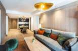 This stunning apartment boasts a spacious open-plan living area with a cozy sofa and plush pillows, perfect for relaxing after a day on the slopes.