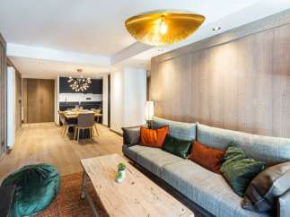 This stunning apartment boasts a spacious open-plan living area with a cozy sofa and plush pillows, perfect for relaxing after a day on the slopes.