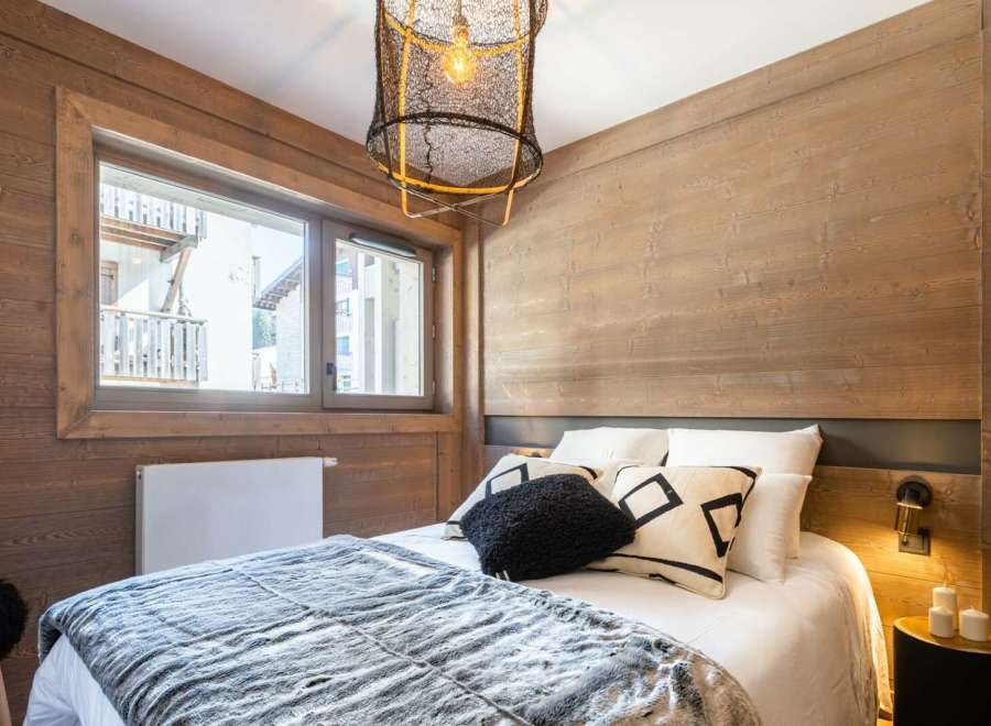 Cozy mountain chalet bedroom with wooden walls and a comfy bed.